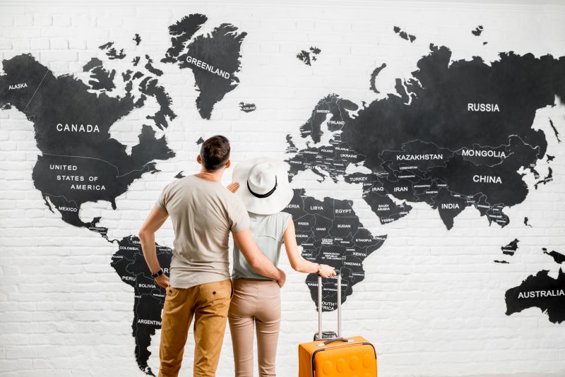 Young-couple- of-travelers standing back near-the-big-world-map