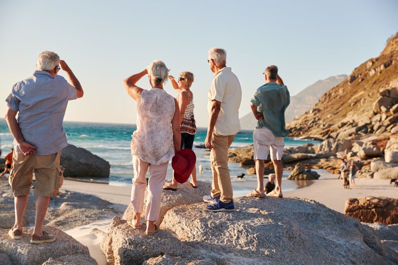Rear View Of birdwatchers Standing On Rocks Looking Out To Sea